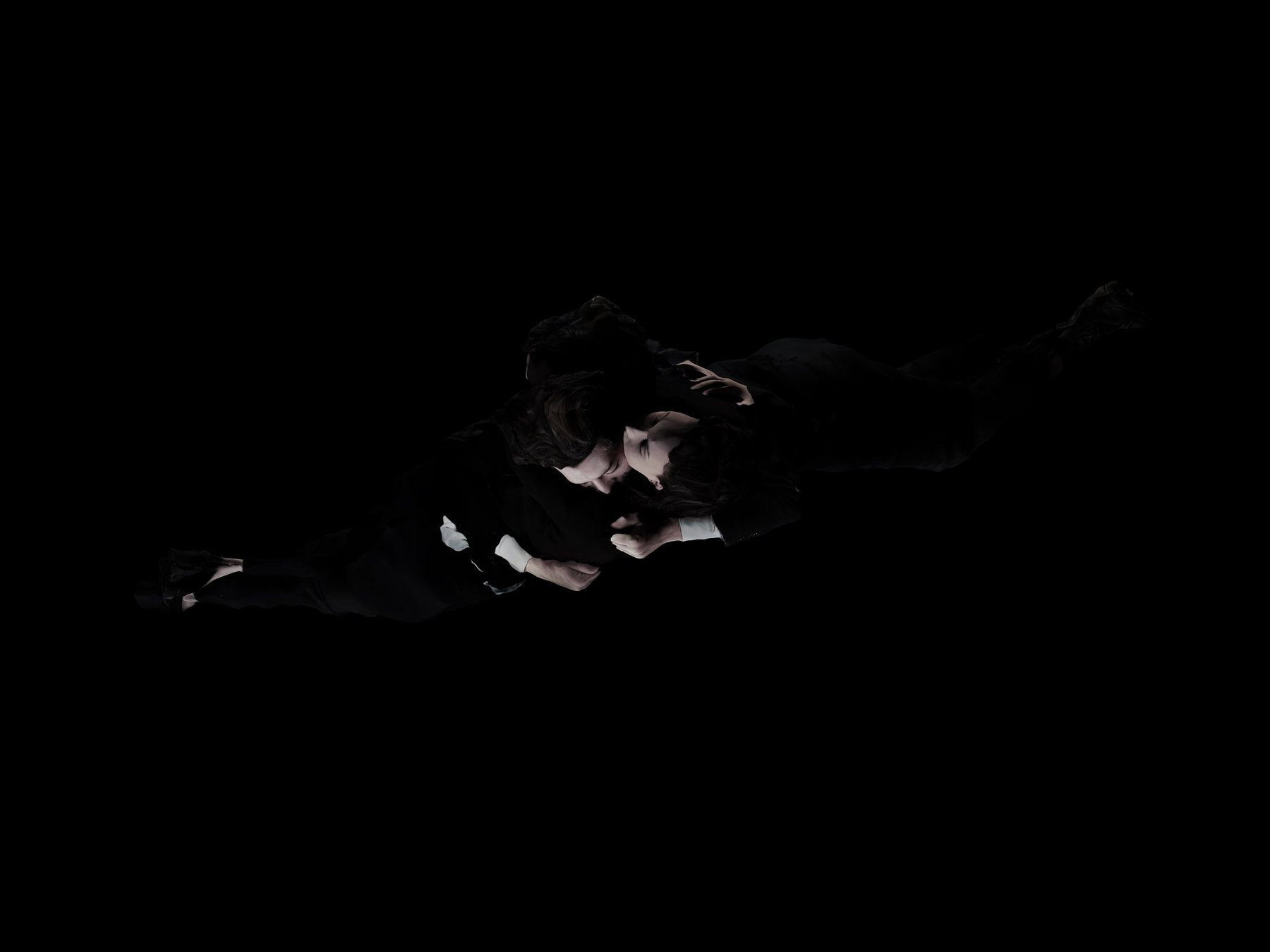Two figures in dark suits lying together in an embrace, almost lost in black darkness; Encounter figure study.