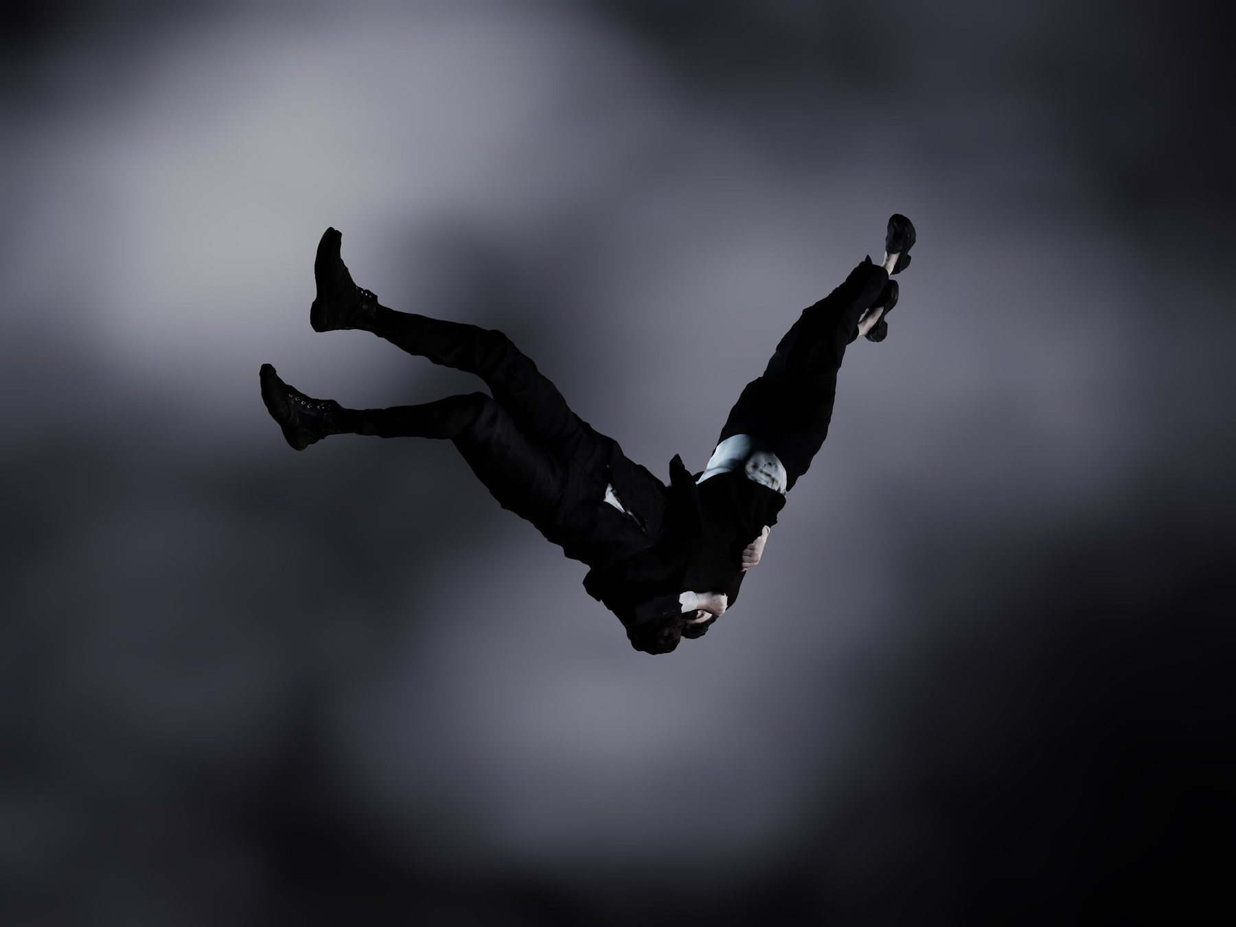 Dark-suited figure falling head-down through a cloudy grey sky, legs raised; Encounter figures study.