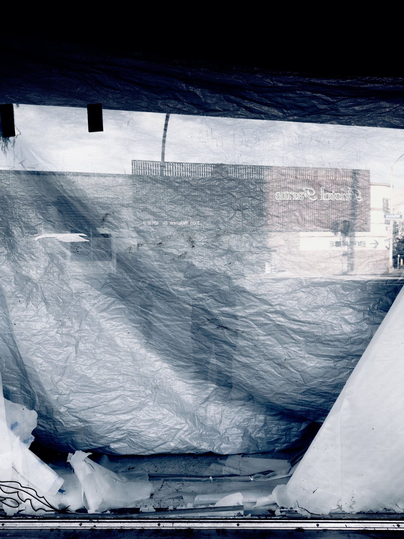 No End In Sight 122: A window covered by crumpled grey plastic sheeting in cool blue tones, with a faint figure and a shop sign reflected in the upper right.