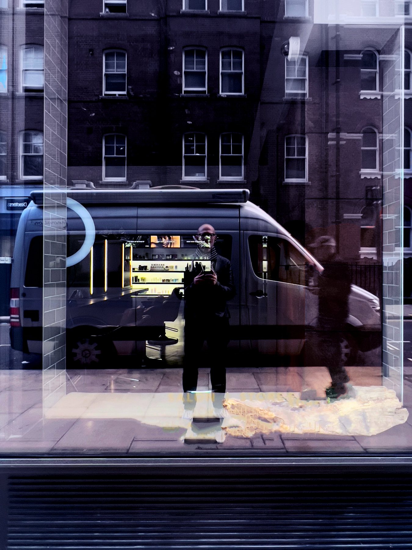 No End In Sight 044: The artist reflected in a window with a parked van, interior shop lights and a ghostly walking figure, in a purple and blue palette.