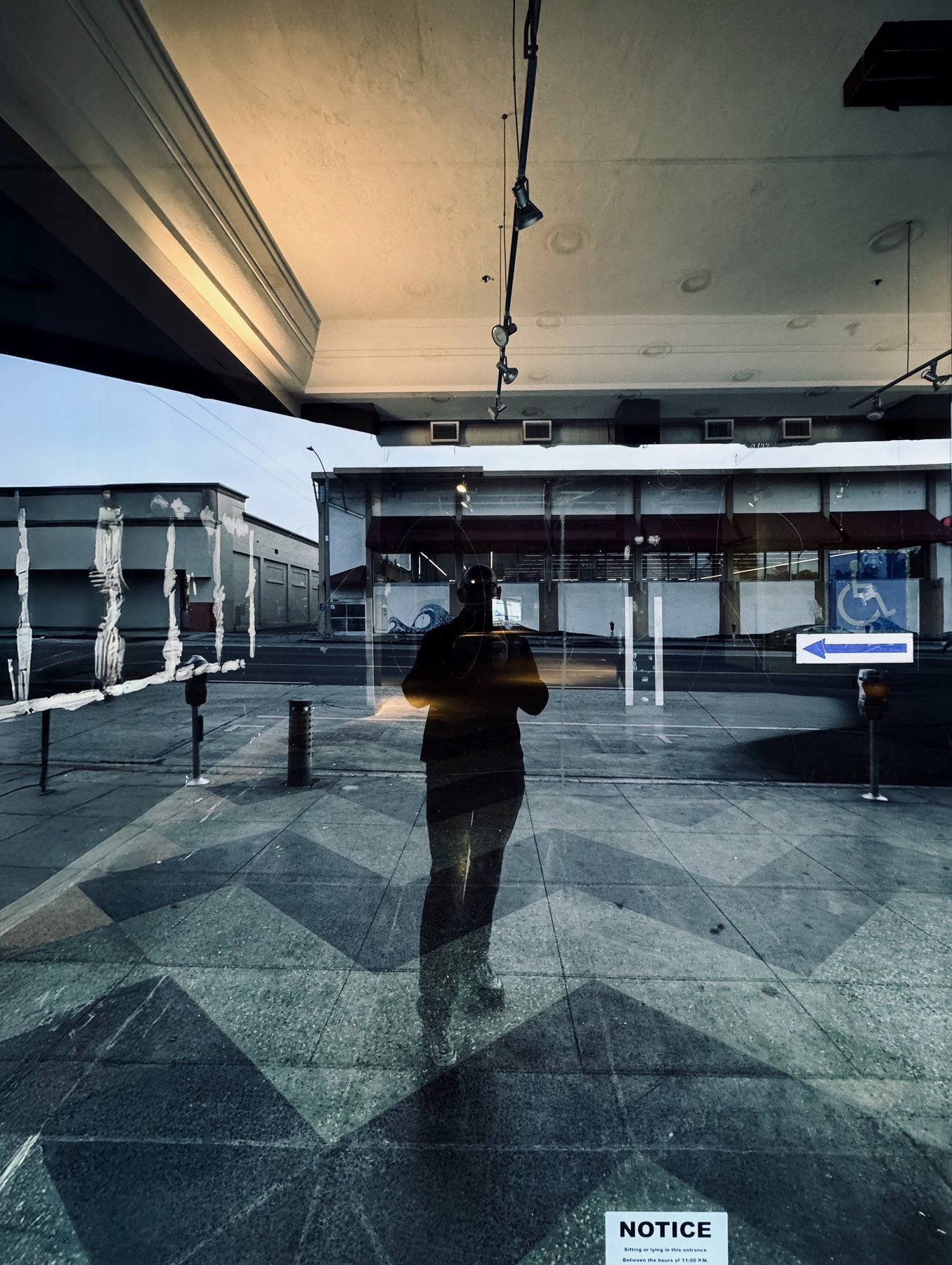 No End In Sight 114: The artist's shadowy figure in a window under a high ceiling, with a chevron-patterned floor, a parking sign and a NOTICE card at the bottom.