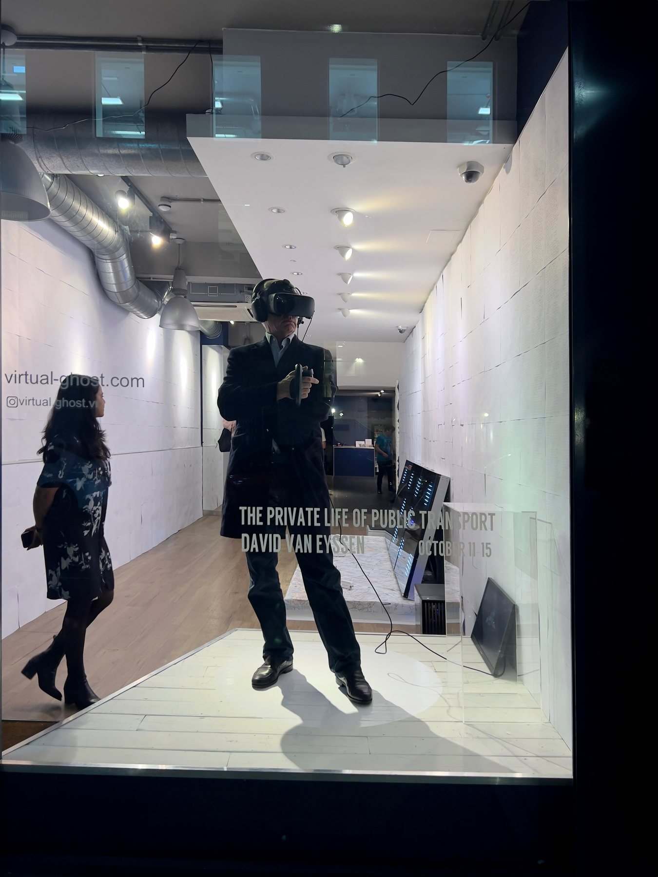 A visitor in a headset in a shopfront window with the title The Private Life of Public Transport, David Van Eyssen, October 11-15.